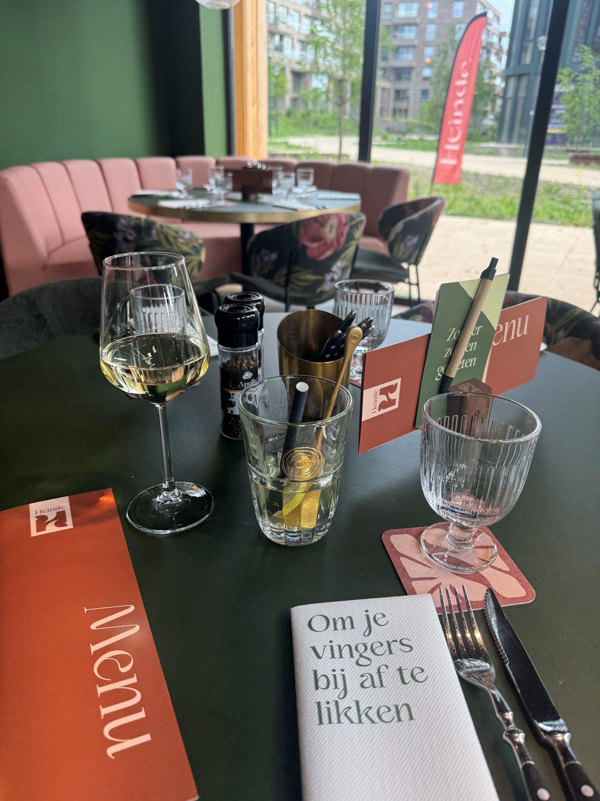 Gedekte tafel bij restaurant Heinde met menukaart en glas wijn