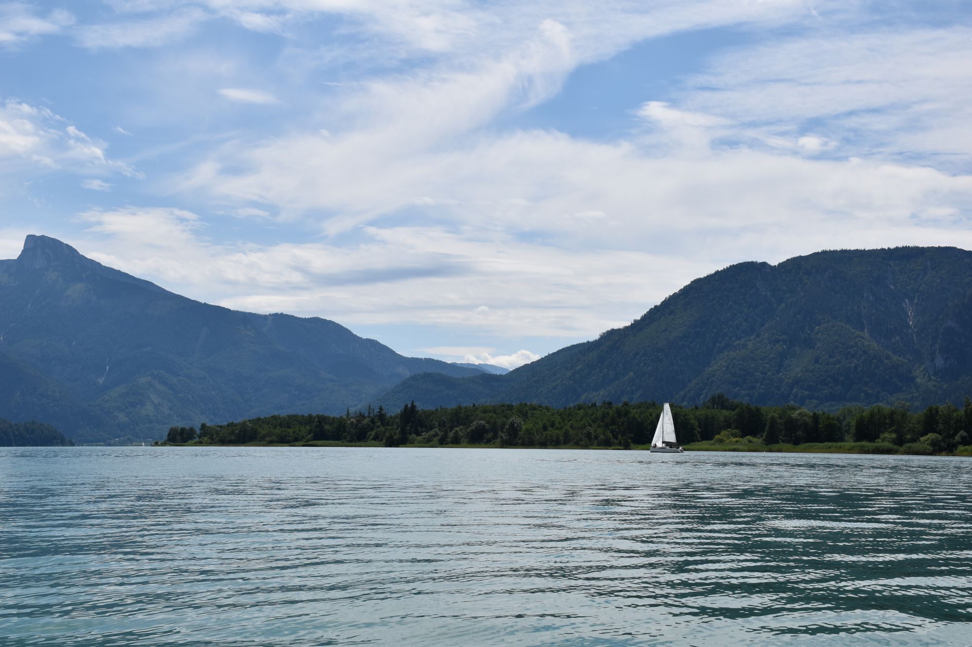 Uitzicht over de Mondsee in Oostenrijk met bergen, water en een zeilboot