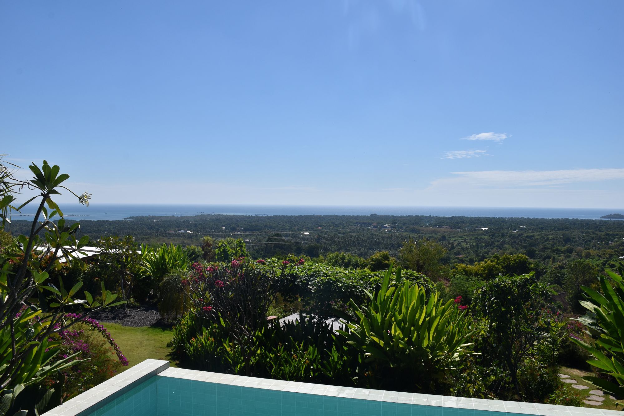 Uitzicht vanuit een villa in Pemuteran op Bali met privézwembad, tropische tuin en de zee op de achtergrond