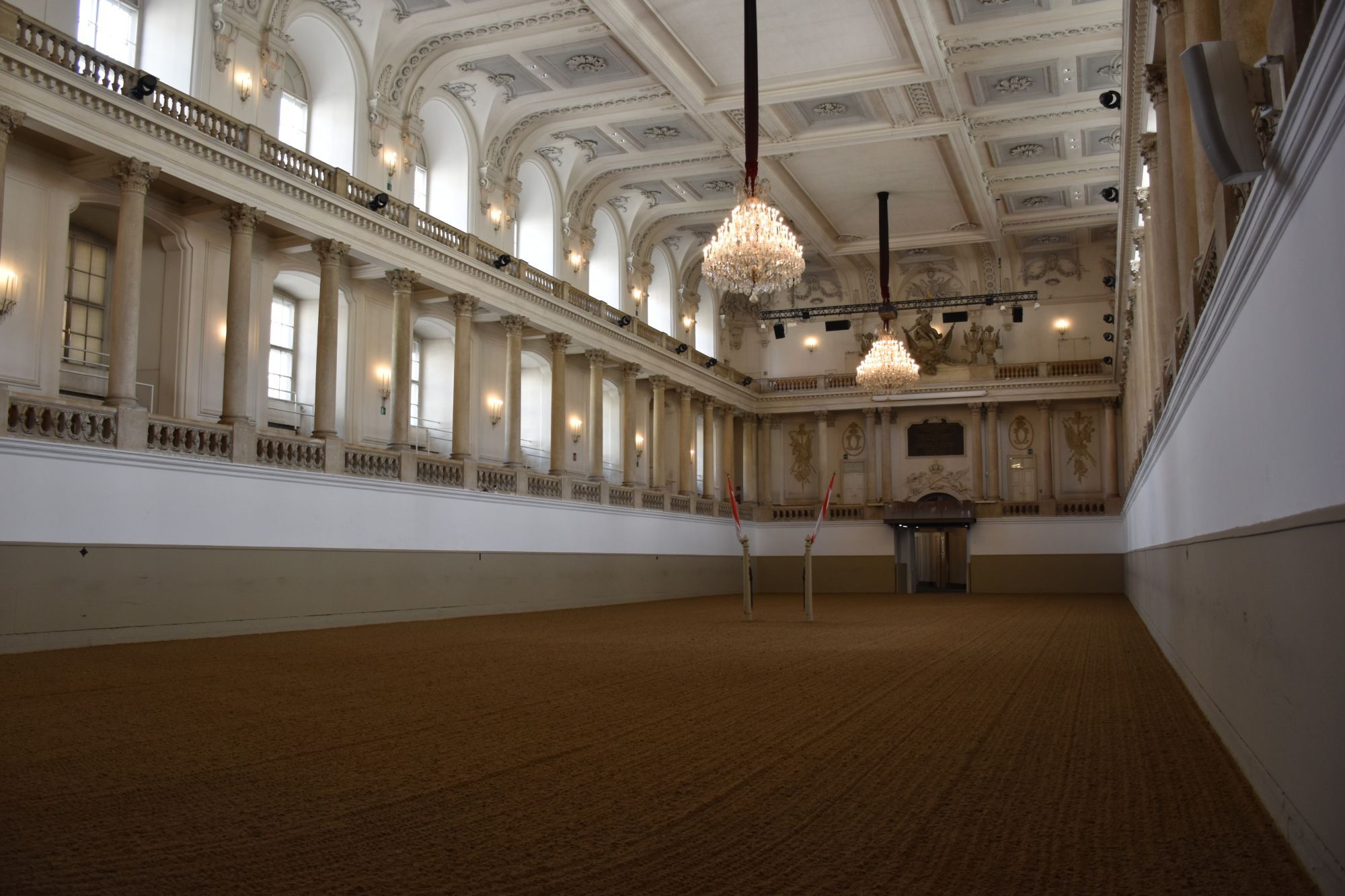 Historische rijzaal van de Spaanse Hofrijschool in Wenen met kroonluchters en witte zuilen